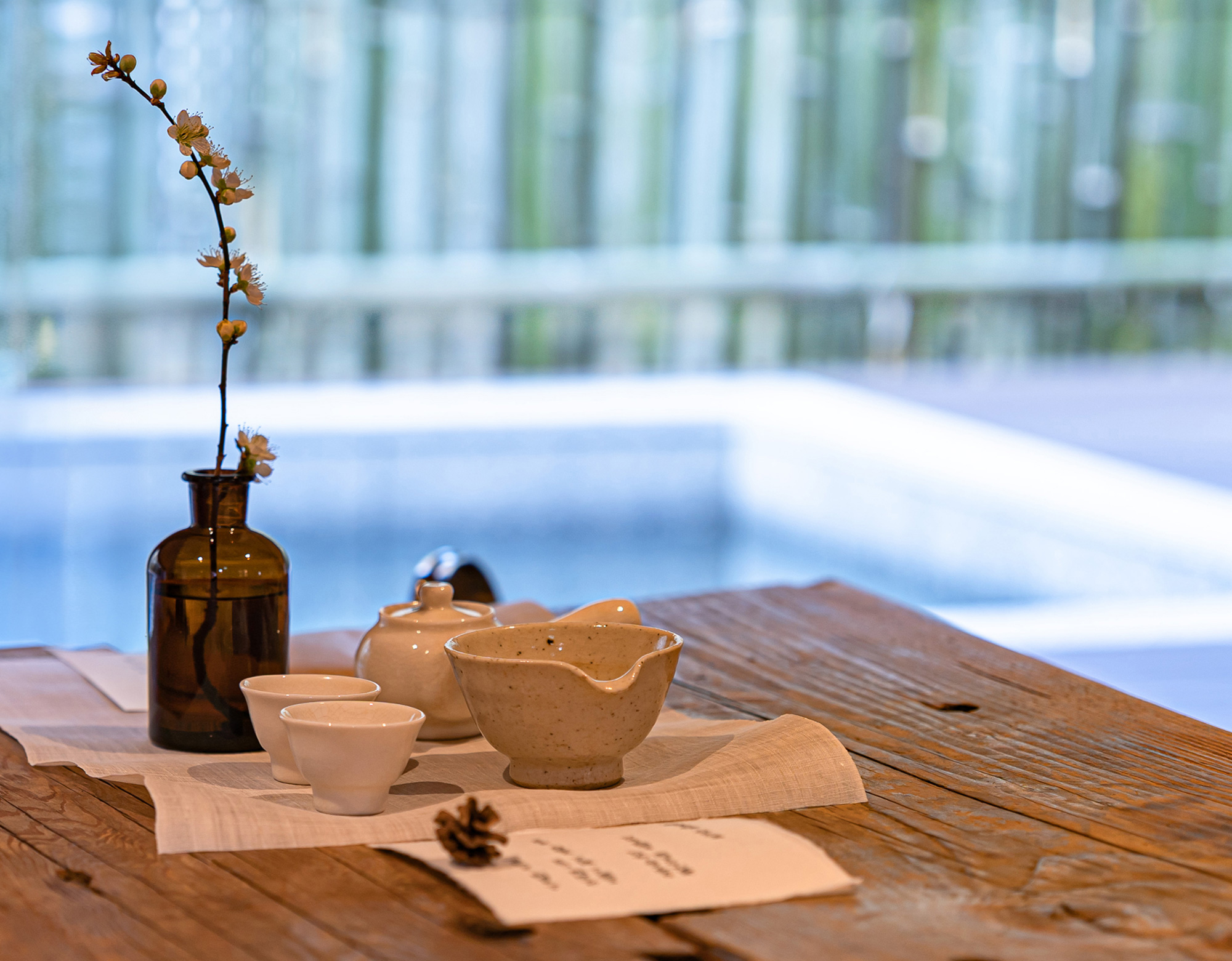 A window with plum blossom branches and tea utensils, with the hot bath visible beyond