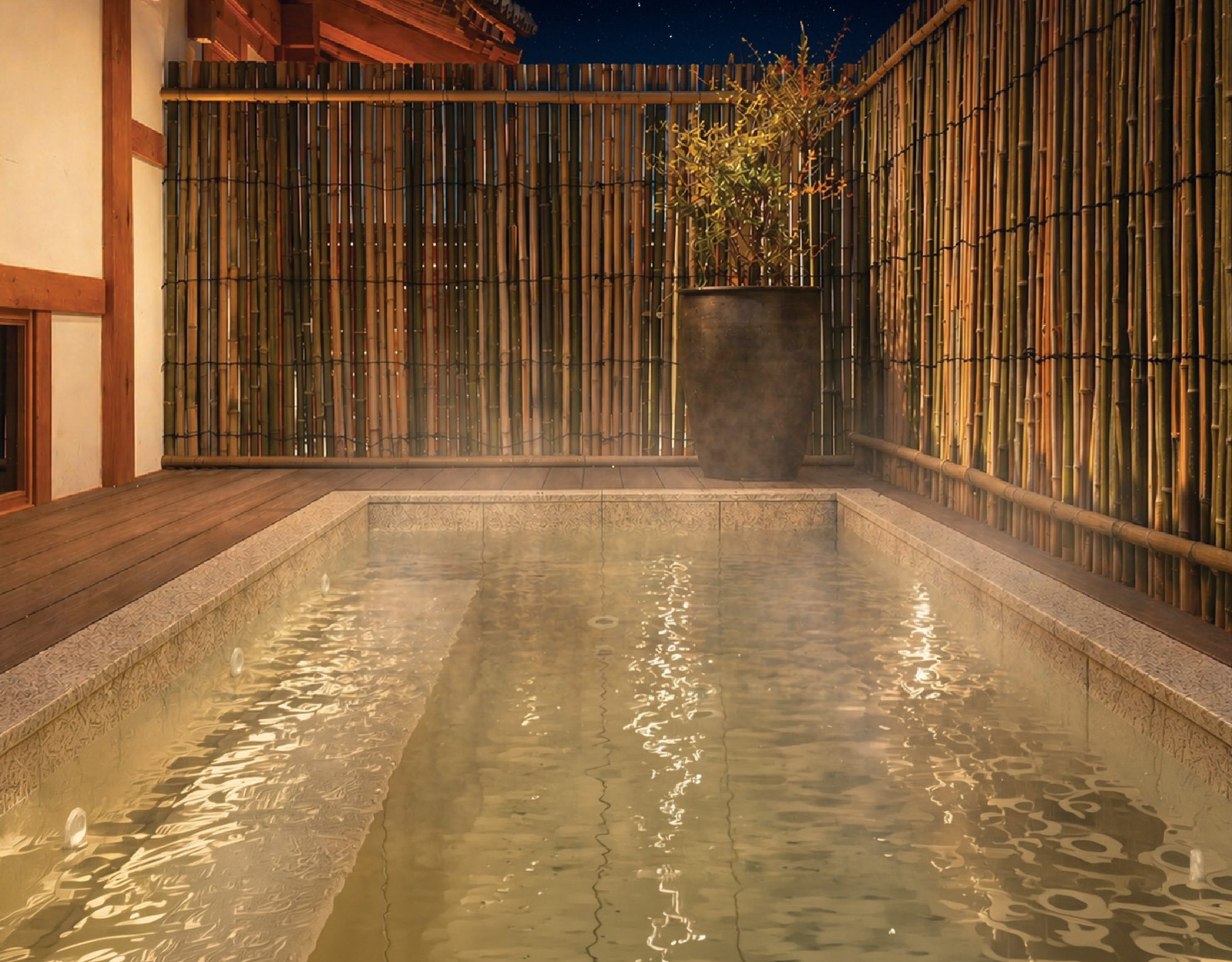 An outdoor hot bath with steam rising beneath a bamboo fence