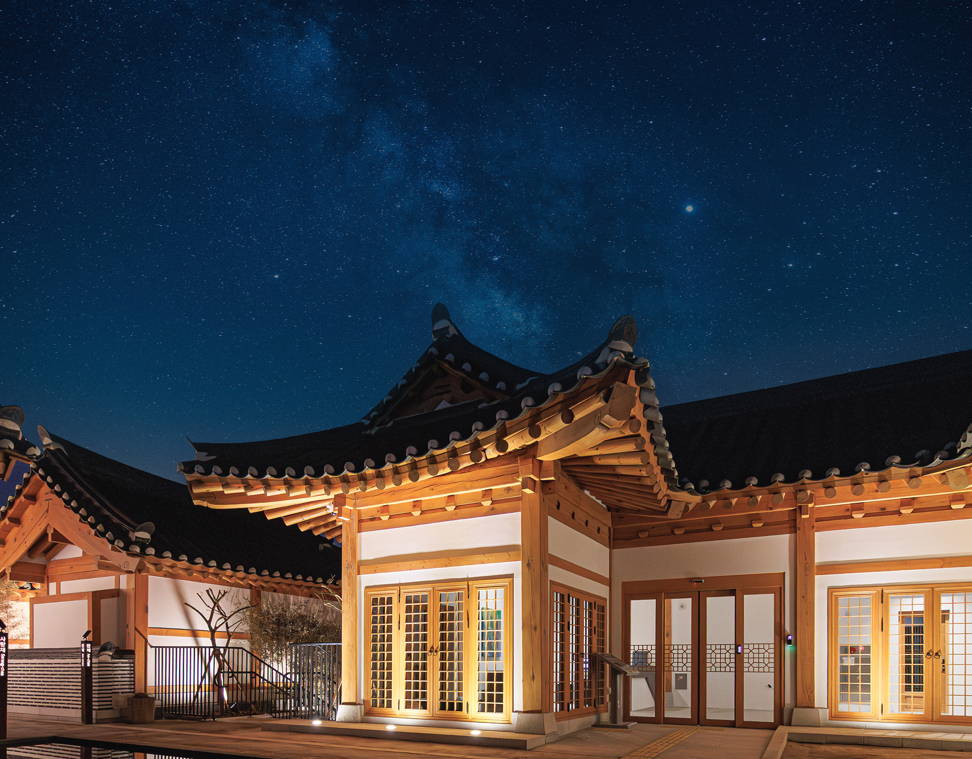 A private hanok villa lit up under a night sky with the Milky Way