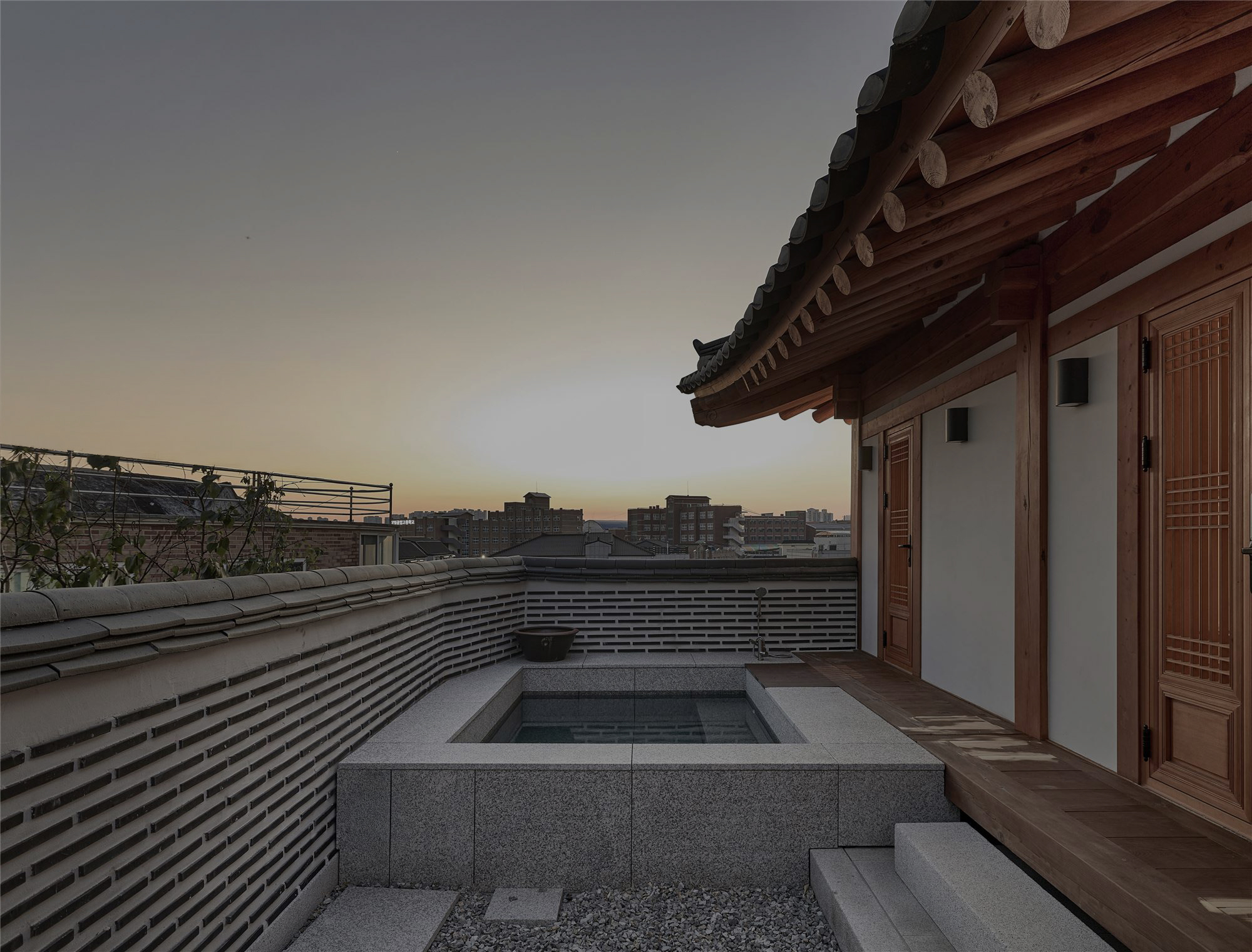 An outdoor hot bath open to the city at sunset