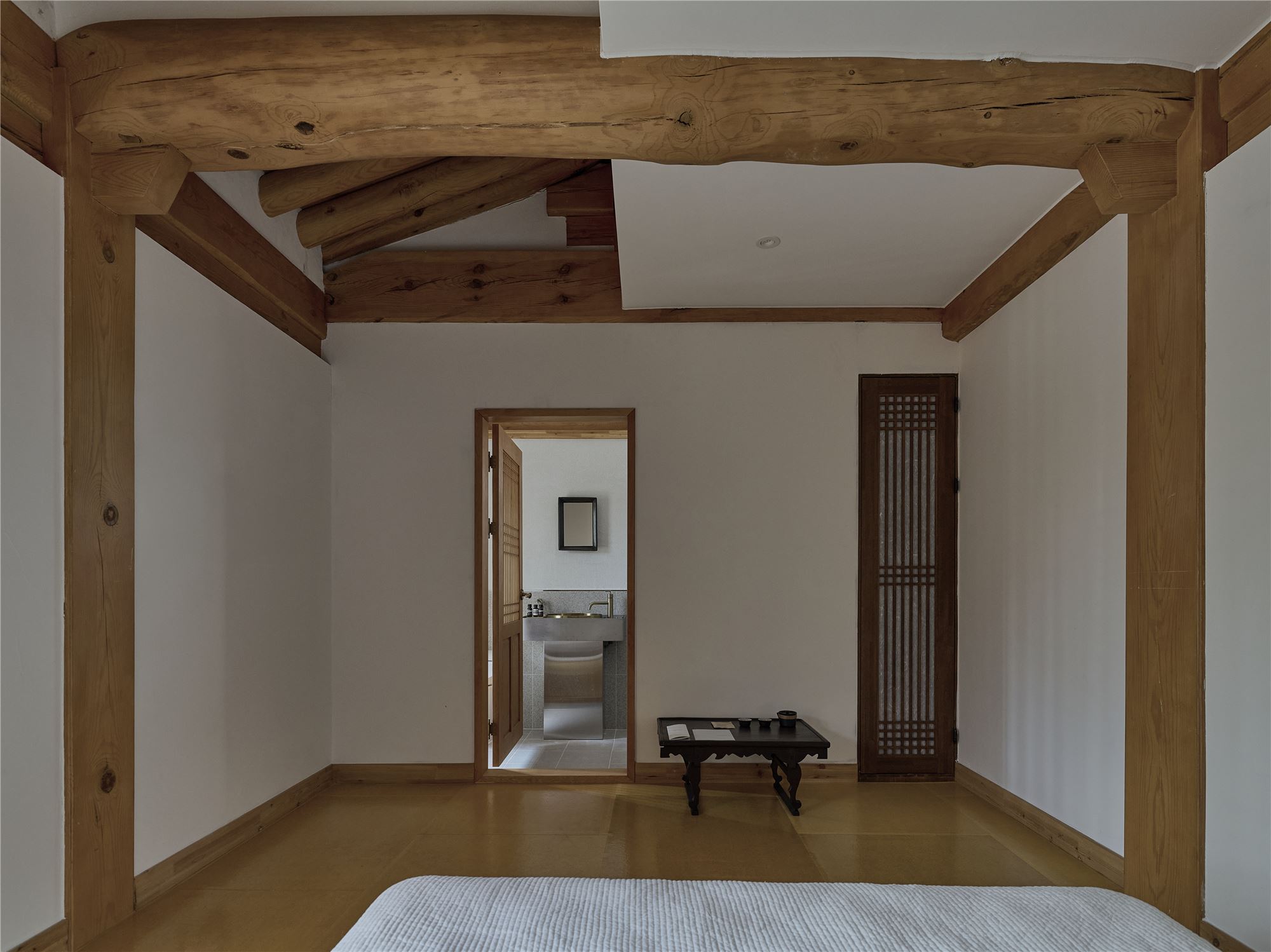 A bedroom under the rafters leading to the bathroom