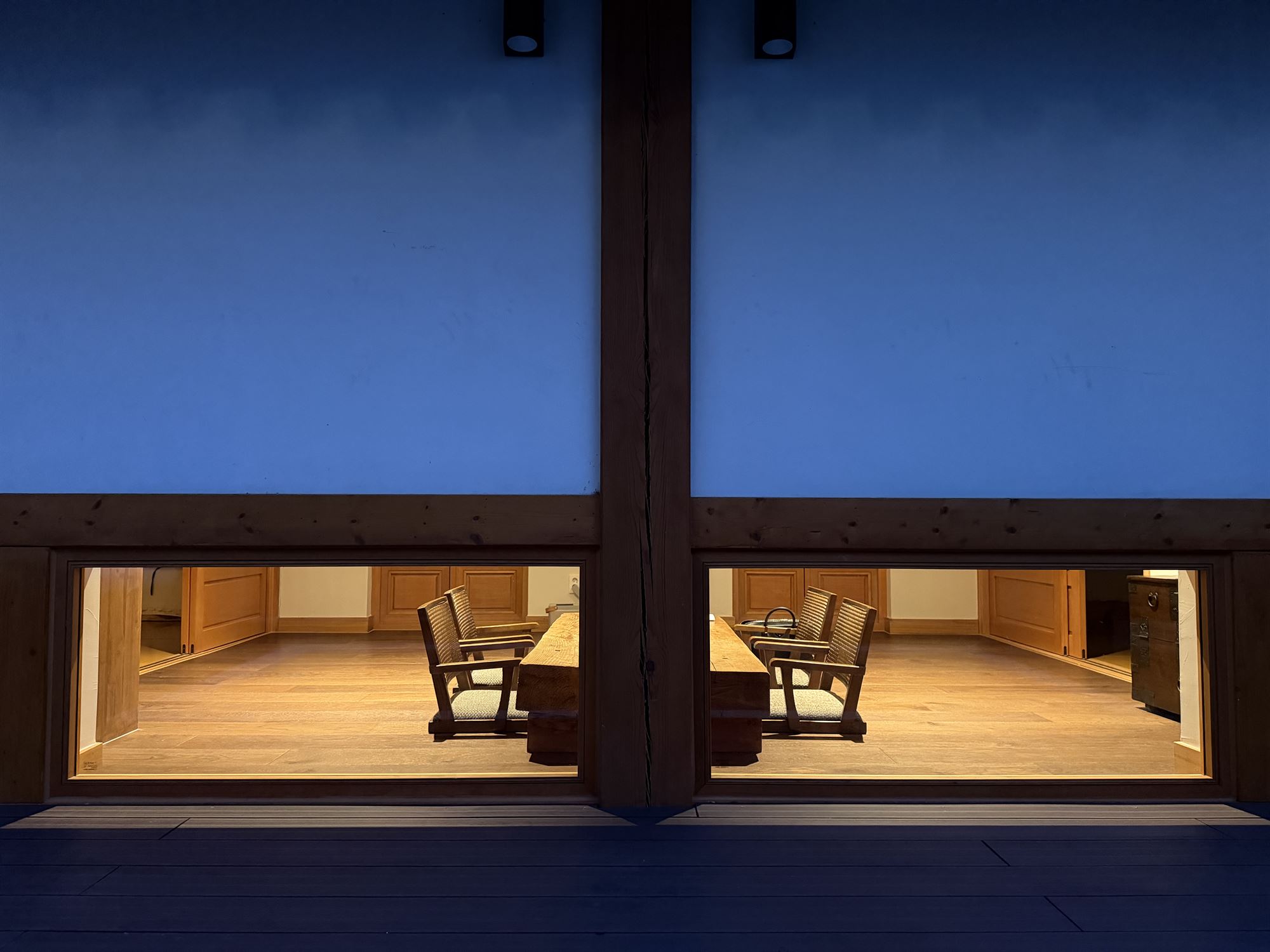 A blue evening, the living room of Byeoldangchae lit up beyond the large window