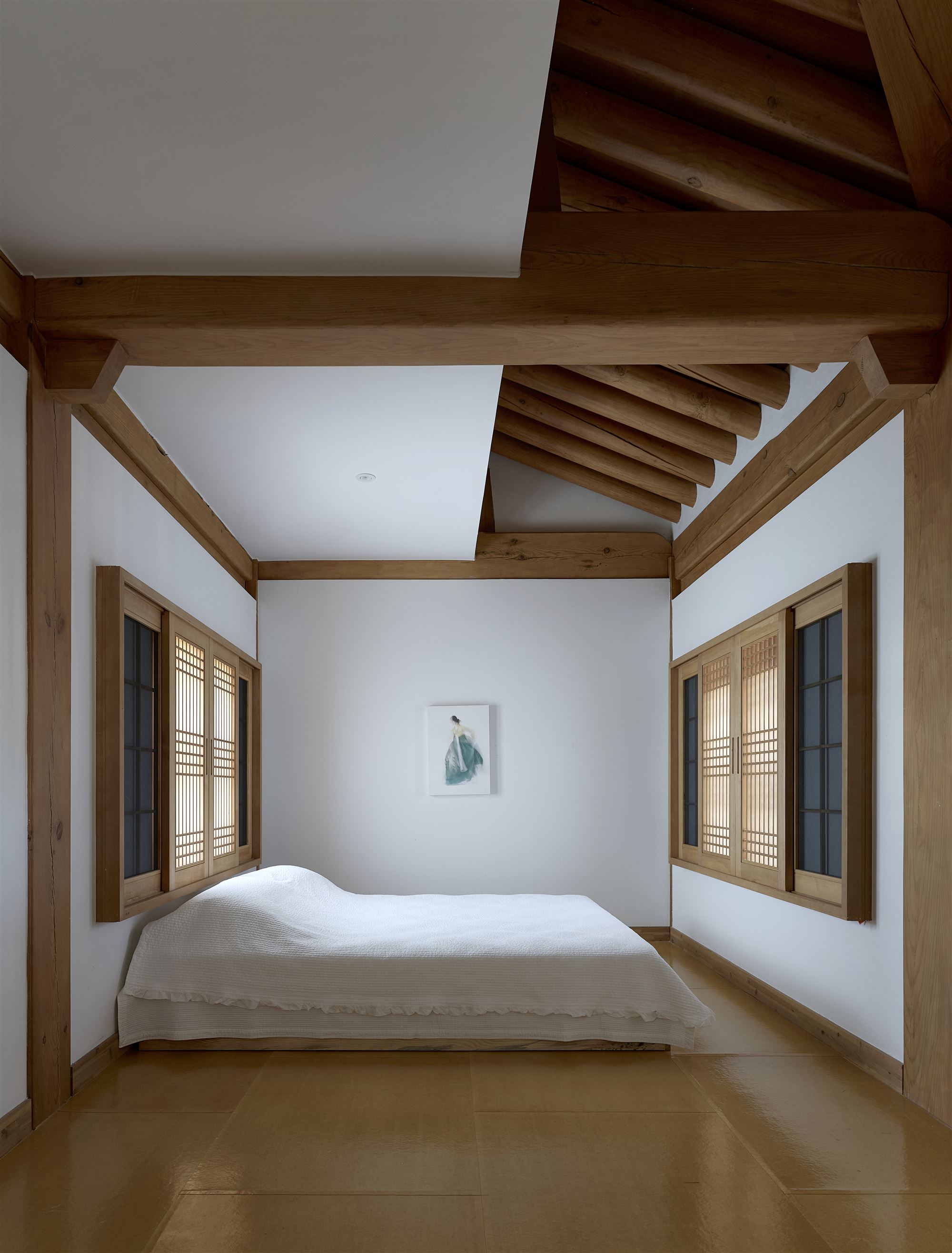 The first bedroom, neat with white bedding beneath the rafters