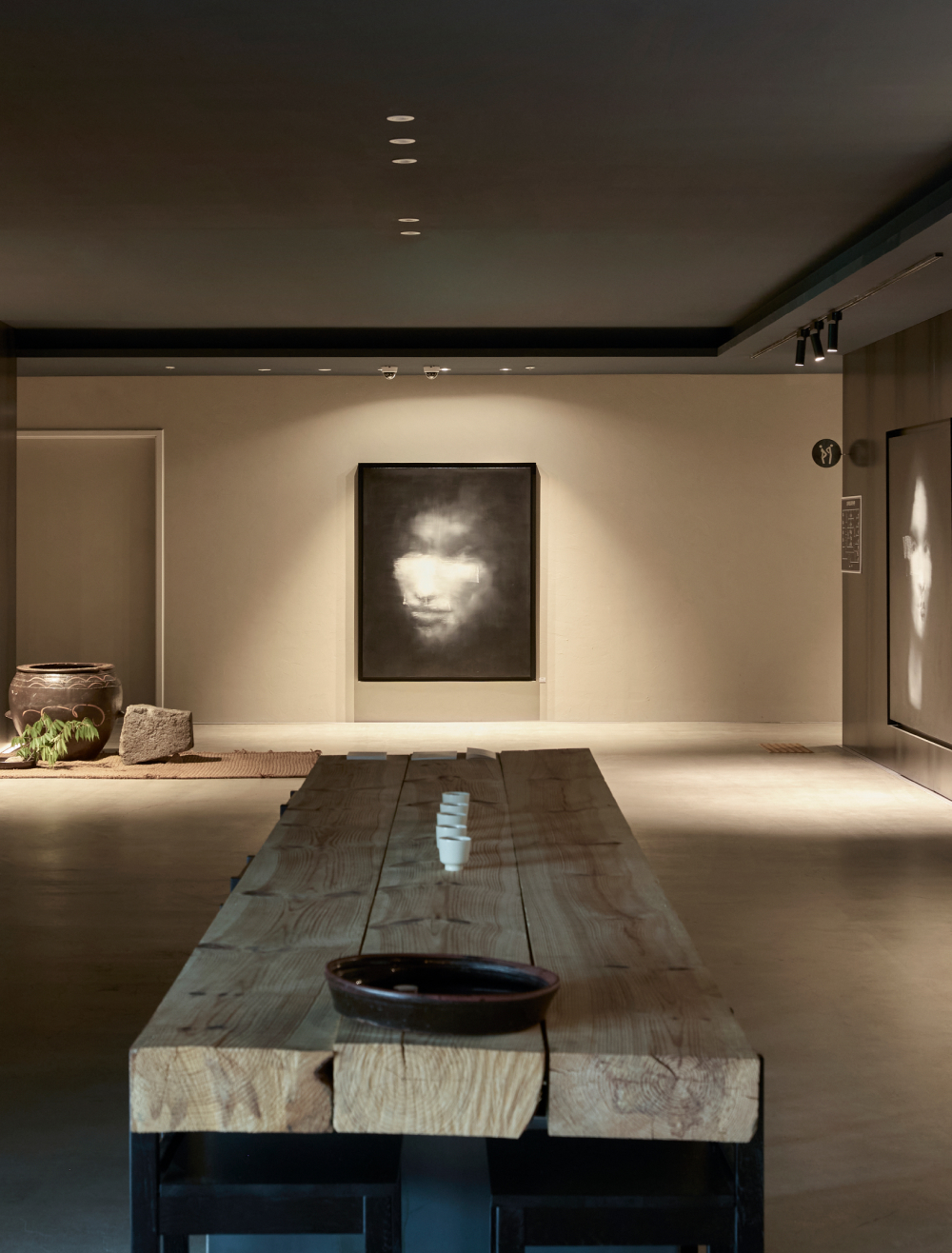 Gallery with a solid wood table beneath portrait paintings