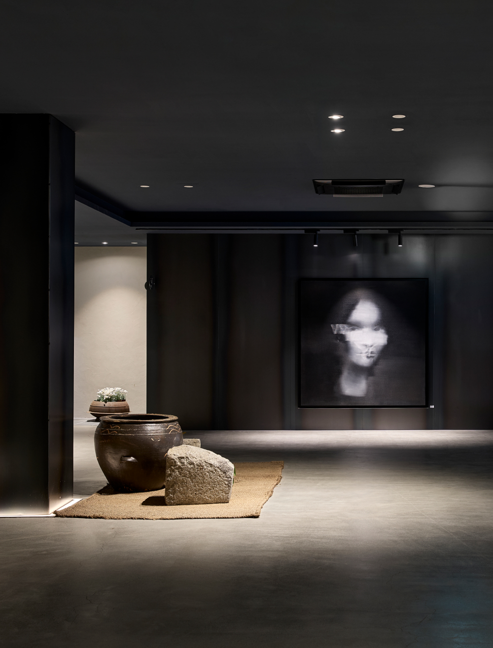 Gallery hall where earthenware jars, stones, and portraits harmonize