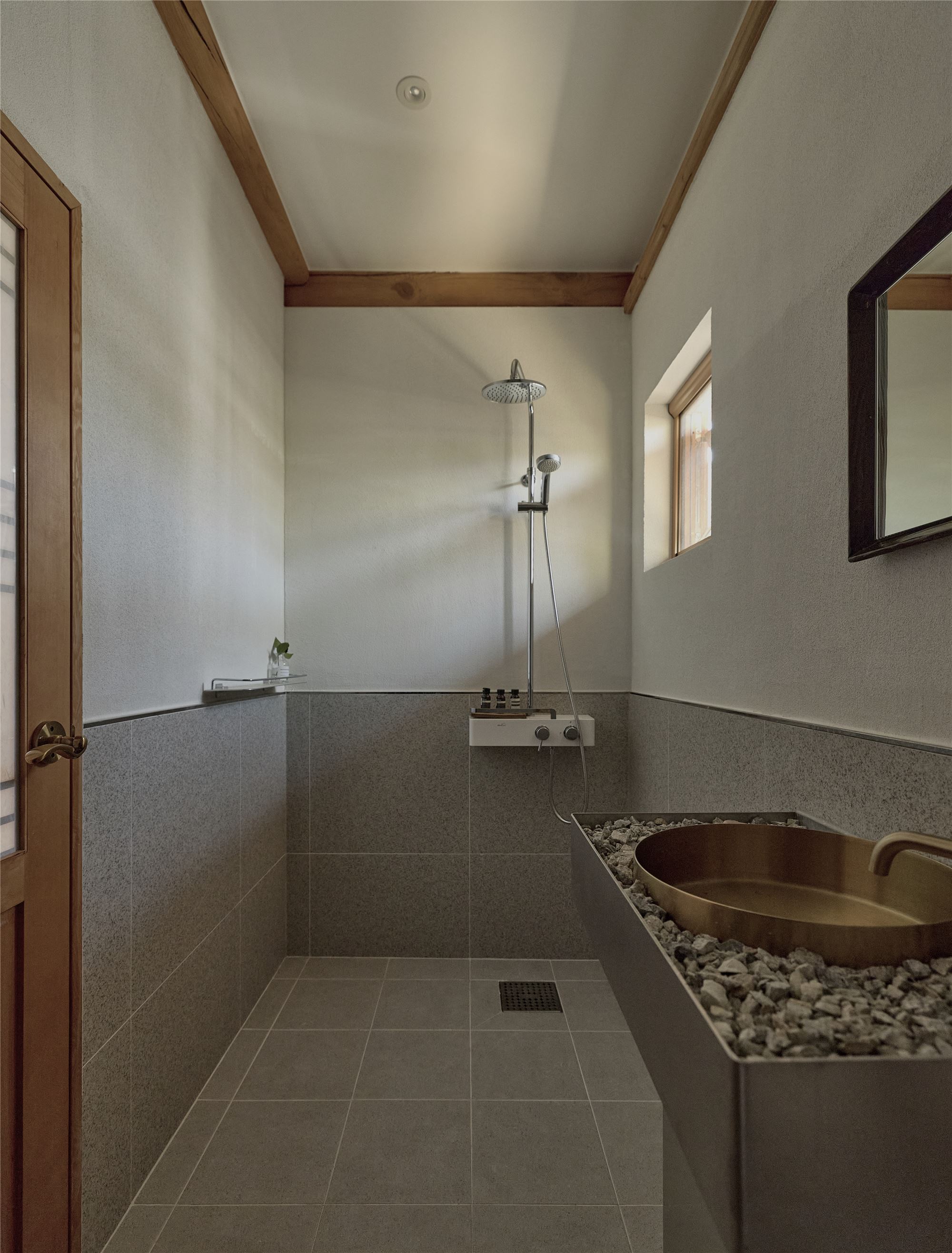 A bathroom with a brass washbasin and smooth pebbles