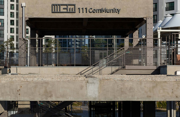 The concrete exterior and outdoor terrace of the former Suwon Tobacco Manufacture Factory, bearing the 111CM logo