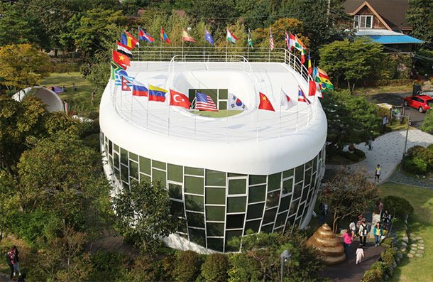 Exterior view of Haewoojae with flags of various nations hanging over its toilet-shaped roof