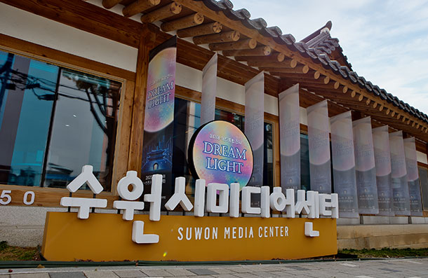 Front view and standing sign of Suwon Media Center, with a Dream Light exhibition banner hanging